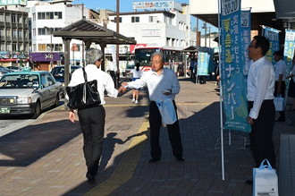 写真：のぼり旗を掲げて駅の利用客にポケットティッシュを配る様子2