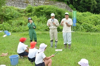 写真：県の農林事務所職員の話を座って聞く児童三人の様子