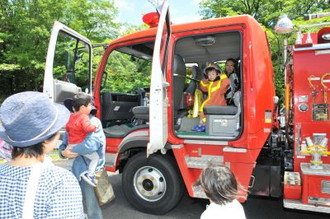 写真：ヘルメットと消防服を着て消防車に乗っているこどもとお母さん