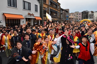 写真：餅投げで、投げられた餅を受け止めようとする笑顔のダンサーたち