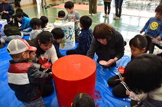 写真：だるまを赤い色で塗り上げる、子供たちと指導員