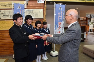 写真：釜戸中学校生徒会長から大湫公民館長へ懐中電灯を渡している様子