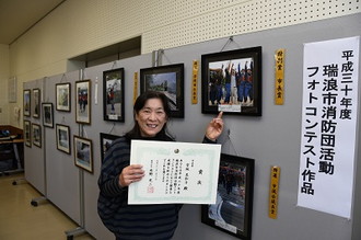 写真：市長賞に選ばれた宮地さんが賞状をもって作品を指さす様子