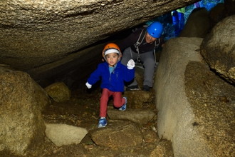 写真：ヘルメットをかぶって穴をくぐる子どもと、身をかがめてくぐる男性