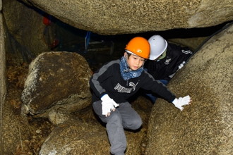 写真：大きな岩のすきまを、岩を乗りこえるように進む子どもの様子