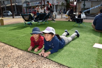 写真：芝生の上に腹ばいになっている二人の子ども