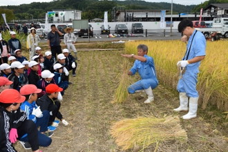 写真：稲の束ね方を真剣に聞いてる子どもの様子