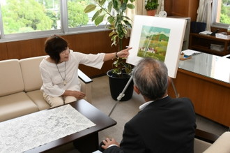 写真：作者自ら「隠し絵」を説明する中山さんと、聞き入る教育長