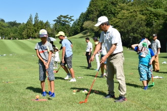 写真：ボールの打ち方を習う、明世小学校の児童たち