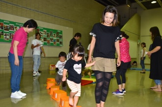 写真：親御さんと手をつないでステップを渡るお子さんの様子