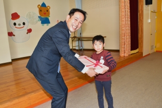 写真：おりべ会会長が園児に紙芝居を渡す様子
