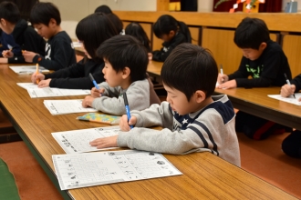 写真：低学年児童がペン習字する様子