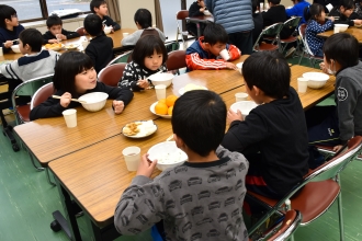 写真：児童が机で七草がゆを食べている様子