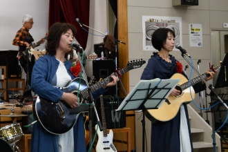 写真：女性2人がギターを演奏し、歌を演歌っている様子