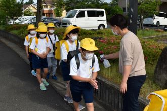 写真：児童が霧吹きで手を消毒している様子