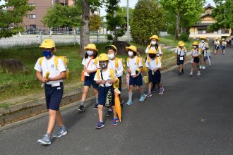 写真：児童たちが分団で校舎前を歩いている様子