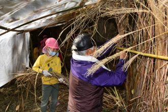 写真：秘密基地の壁にわらを編み込む様子