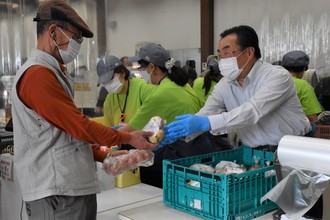 写真：笑顔で野菜を渡す市長